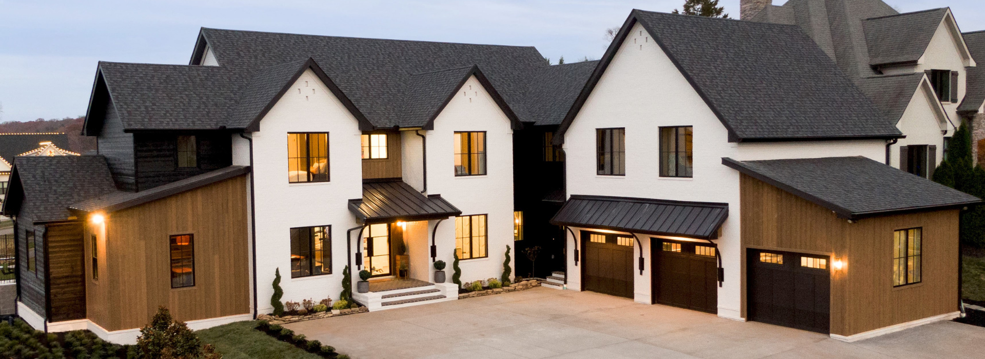 Modern suburban mixed materials front exterior at dusk with brick and thermally modified wood siding Lost Trail Black Forest