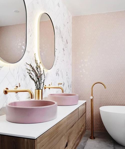Bold light pink bathroom with pink wash basin, white accents, and gold fixtures
